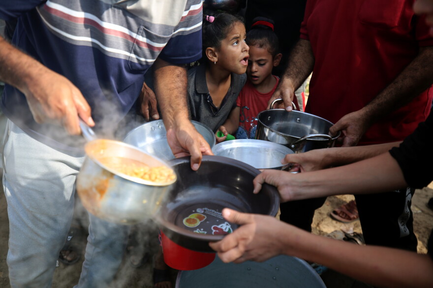 Palestinian children receive food between tents set up for Palestinians seeking refuge on the grounds of a United Nations Relief and Works Agency for Palestine Refugees (UNRWA) centre in Khan Yunis in the southern Gaza Strip on October 24, 2023, amid the ongoing battles between Israel and the Palestinian group Hamas.
