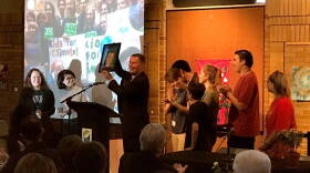 Indianapolis Mayor Joe Hogsett accepts a gift from Cora Gordon (clapping, right) and other members of Youth Power Indiana, which pushed for a city-county climate resolution earlier this year.
