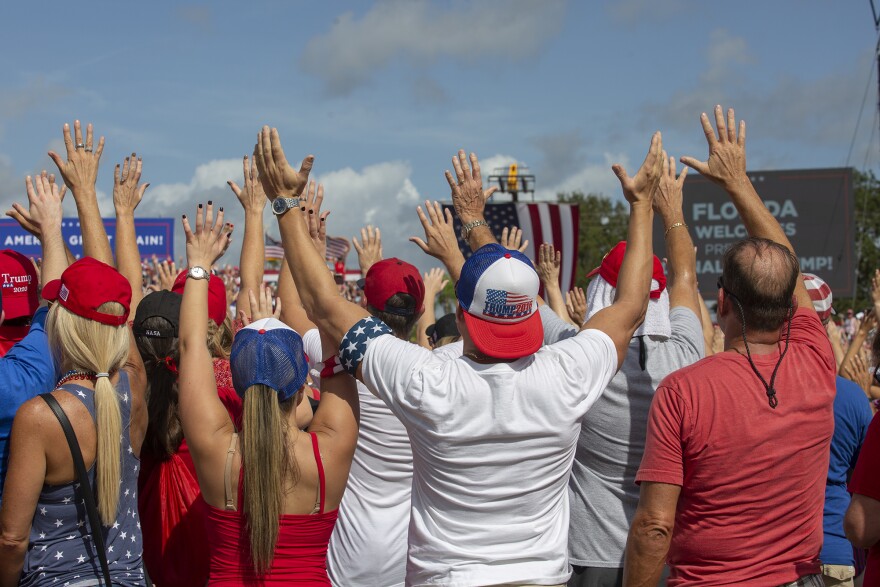 people at political rally waving hands in air