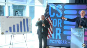 Gov. Asa Hutchinson motions to a graphic displaying the state's computer science enrollment at a news conference in downtown Little Rock.