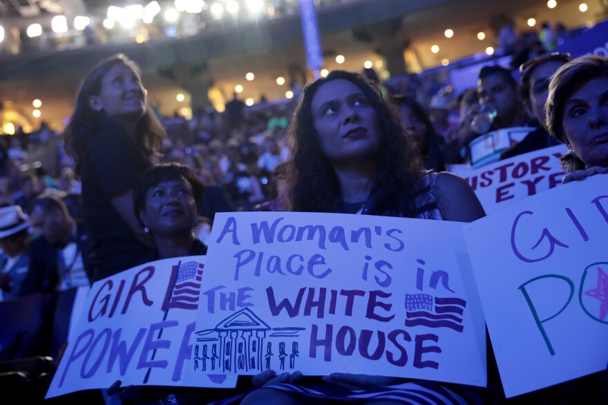 Delegates hold up signs on the convention floor in support of Clinton.