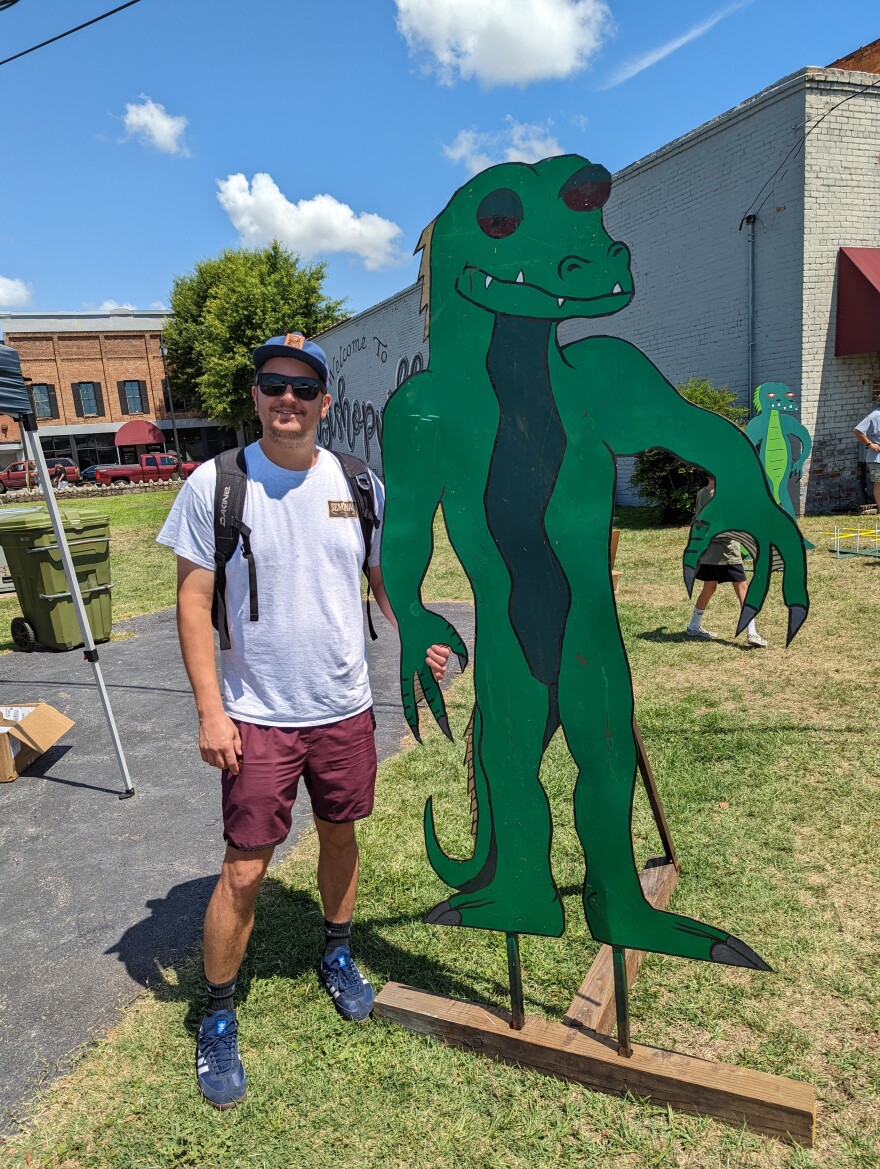 South of Spooky host A.T. Shire poses with a cutout of the Lizard Man at the 2022 Lizard Man Stomp, a yearly event celebrating the folklore of Lee County, SC