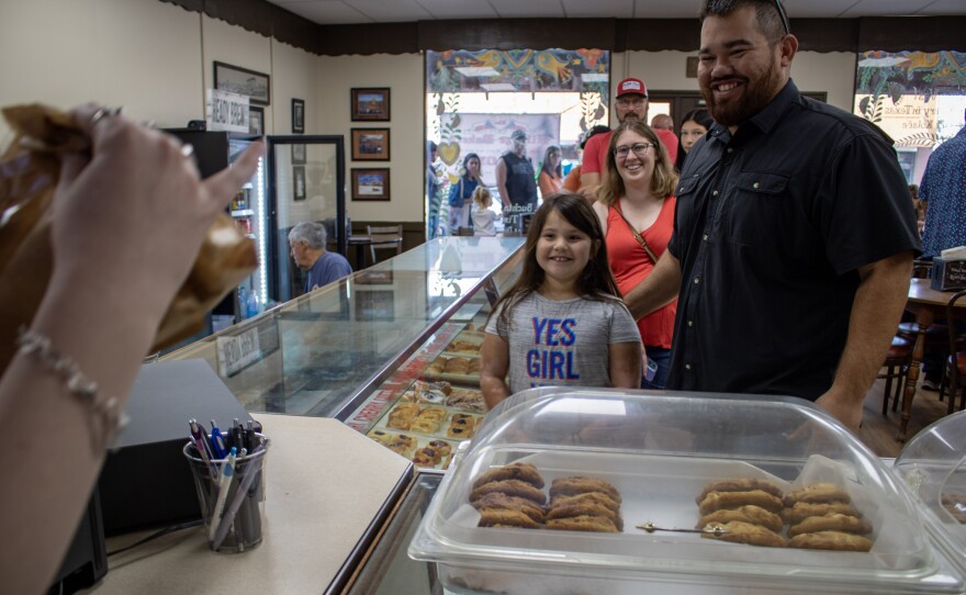 A young girl and her father wait for their pastries during Saturday's reopening at Village Bakery in West, Texas.