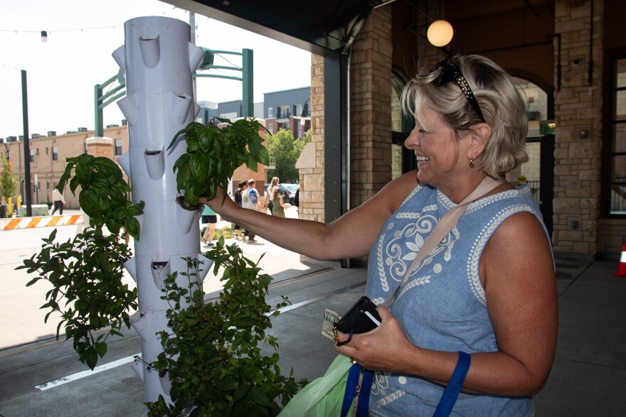 A woman at the Overland Park Farmers' Market purchases herbs from a hydroponic garden.