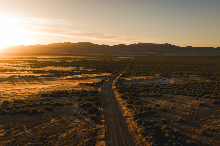 Aerial view of a sunrise over a mostly-empty valley with a road winding through the center.