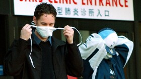 Patients put on face masks as they leave the SARS (Severe Acute Respiratory Syndrome) clinic setup at Sunnybrook & Women's hospital in Toronto, Canada, on 31 March, 2003. (J.P. MOCZULSKI/AFP via Getty Images)