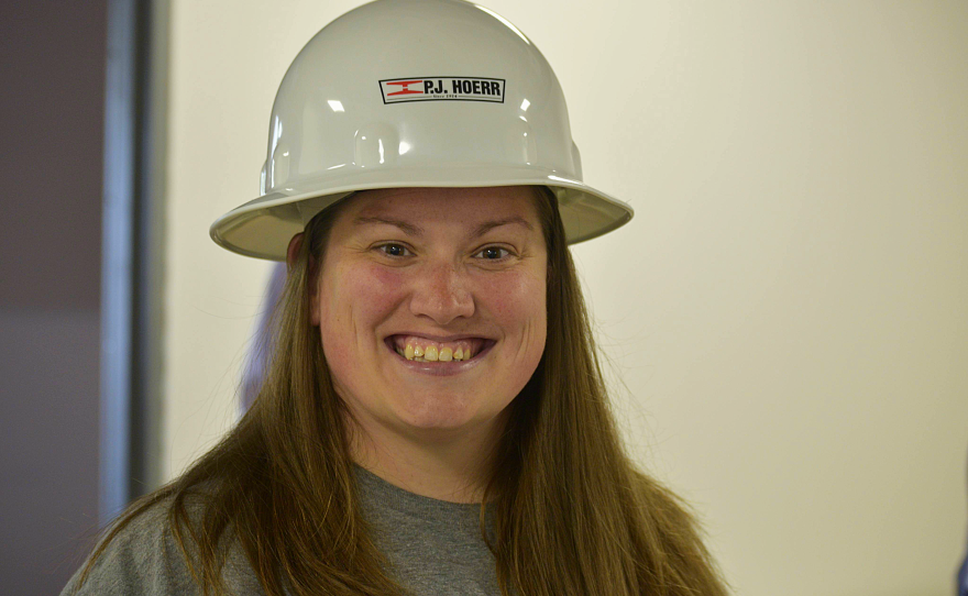 Woman in hard hat smiles.