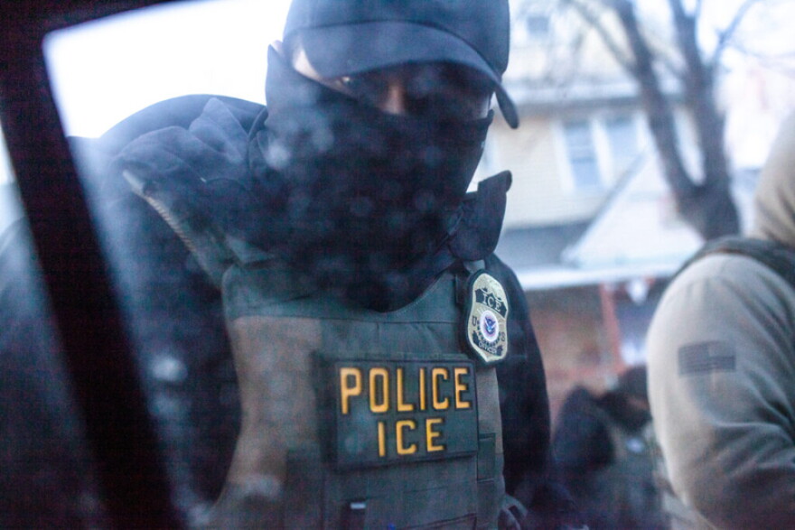 A masked U.S. Immigration and Customs Enforcement agent knocks on a car window in Minnesota on Jan. 12, 2026.