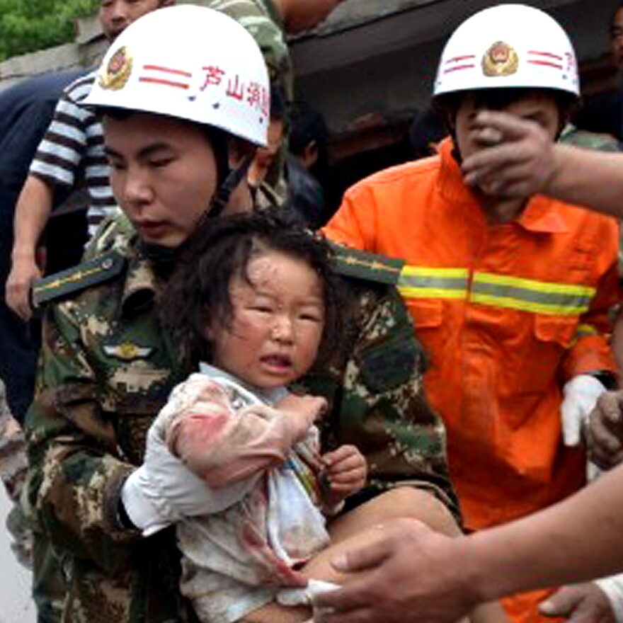 A rescuer carries a child to safety after she was pulled out of her collapsed home after an earthquake hit Ya'an City in southwest China's Sichuan province on Saturday.