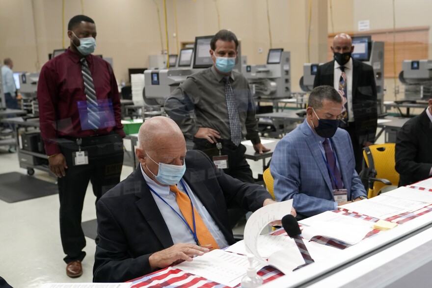 Peter Antonacci, Broward County Supervisor of Elections, left, works with members of the canvassing board on logic and accuracy testing of equipment used for counting ballots, at the Broward Supervisor of Elections Office, Thursday, Sept. 24, 2020, in Lauderhill, Fla.