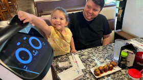 Four-year-old Emily Escalante, tickles the ears of Bella the cat robot, before eating dinner at Ninza Sushi East.