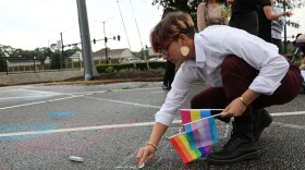 Kellam High student Rose Doucette helps write "Trans Lives Matter" in chalk in the parking lot outside of a Virginia Beach School Board meeting. (Photo by Ryan Murphy)