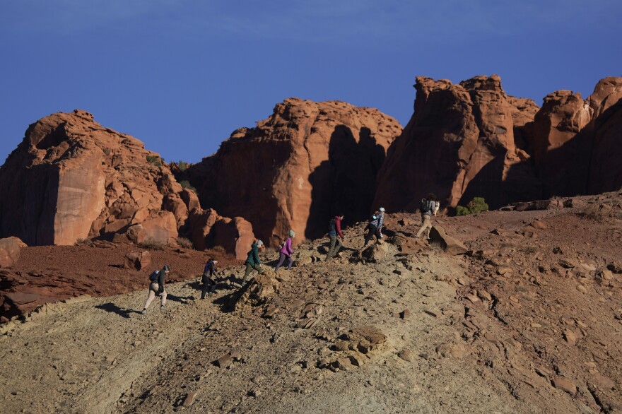 Un groupe de personnes gravit une crête au lever du soleil pour trouver un endroit où observer l'éclipse solaire annulaire qui a commencé peu après 9 heures du matin samedi dans le parc national de Capitol Reef, dans l'Utah.