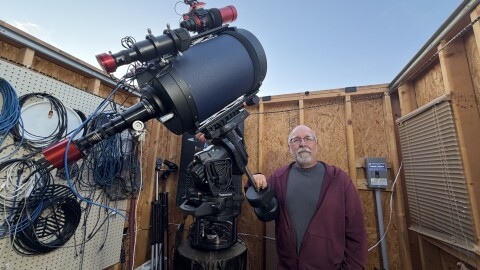 Tom Wildoner stands beside his telescope in his personal observatory.