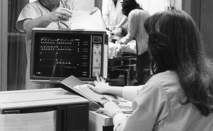 Healthcare workers use the EKG machine in this photo from the 1980s.