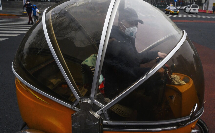 A Chinese man wears a protective mask as he drives a trike in Beijing, China, Thursday. The novel coronavirus has killed more than 2,000 people – most of them in China's Hubei province.