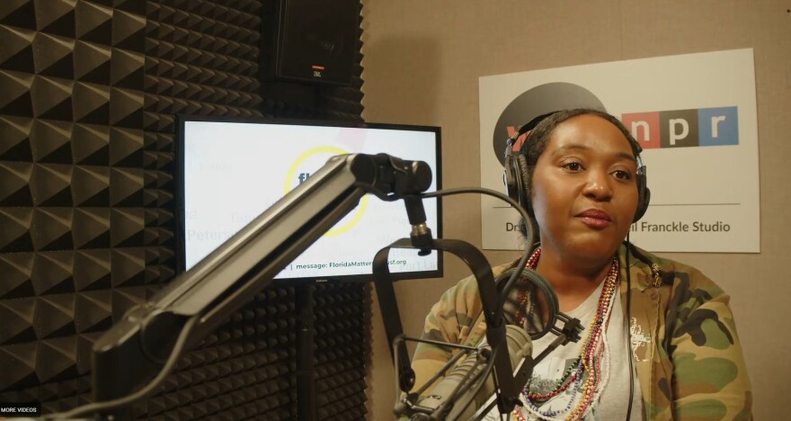 African American woman sits in front of microphone. 