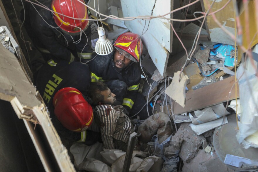 Fire officials rescue an injured person from the debris of a commercial building after an explosion, in Dhaka, Bangladesh, Tuesday.