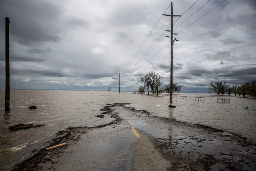 A two lane country road disappears into floodwaters.