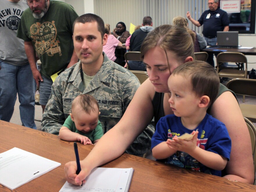 Air Force SSgt. Chris Reed, holding his son Colby, and his wife, Tracy, with son Wesley, seek help at the FEMA office. The couple is looking for housing after their home flooded.