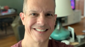 This photo shows a headshot of a man smiling.