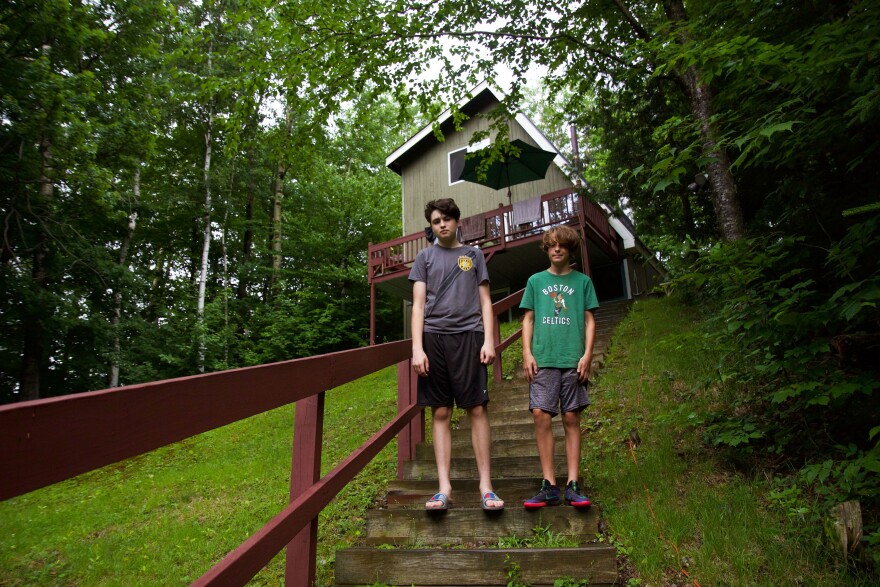 Two boys stand on stairs leading up to a house.