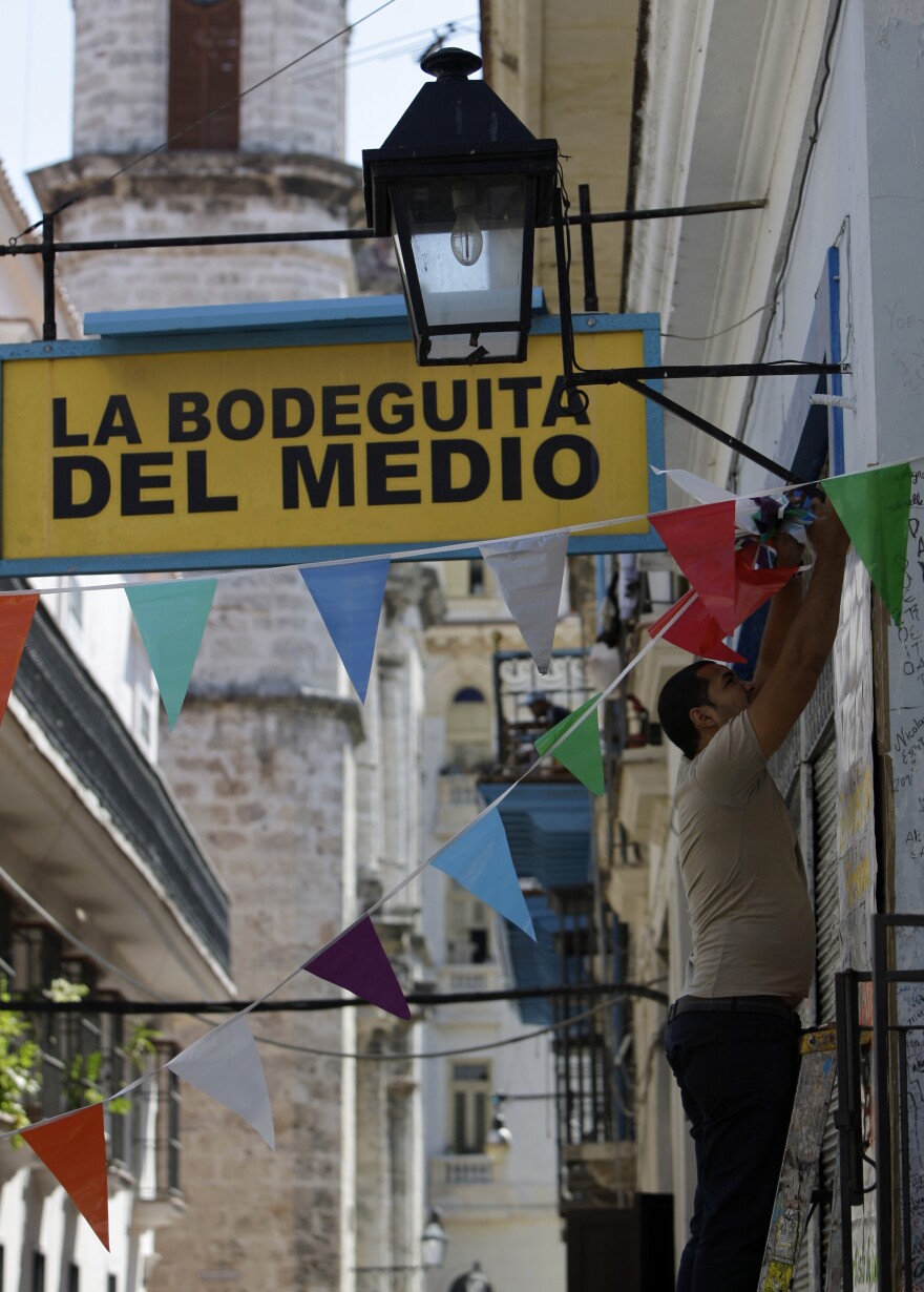 A worker hangs decorative flags outside La Bodeguita del Medio in Old Havana. The restaurant celebrated its 70th anniversary on Thursday.