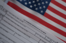 A form for a birth certificate laying on top of a small American flag.