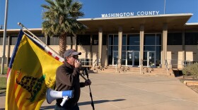 A photo of a protester in St. George carrying a flag that says "Don't tread on me." 