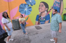 Photo of folks standing against a painted mural of an Indigenous child.