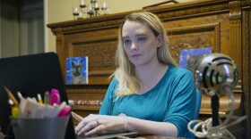 Woman sits in front of computer at home.