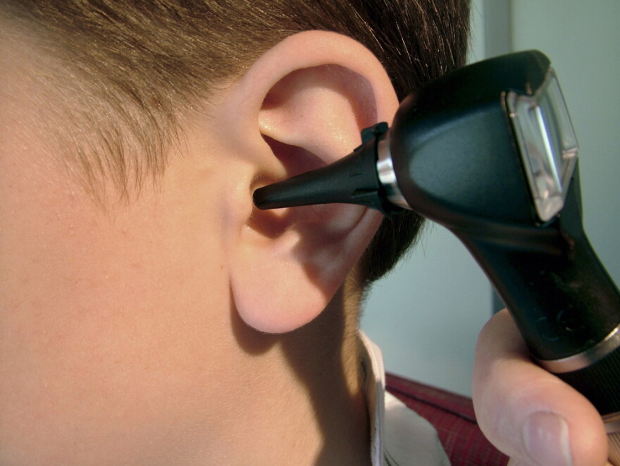 Doctor using otoscope instrument to check child's ear.