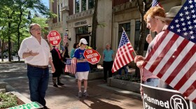 A group of people gather outside Manchester City Hall, some holding signs that say "STOP ABORTION NOW" and another holding a sign that says "Planned Parenthood LIES to you."