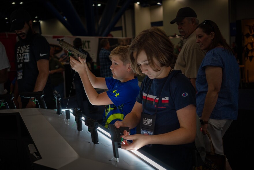 Two kids hold gun at the NRE convention on May 28th, 2022.