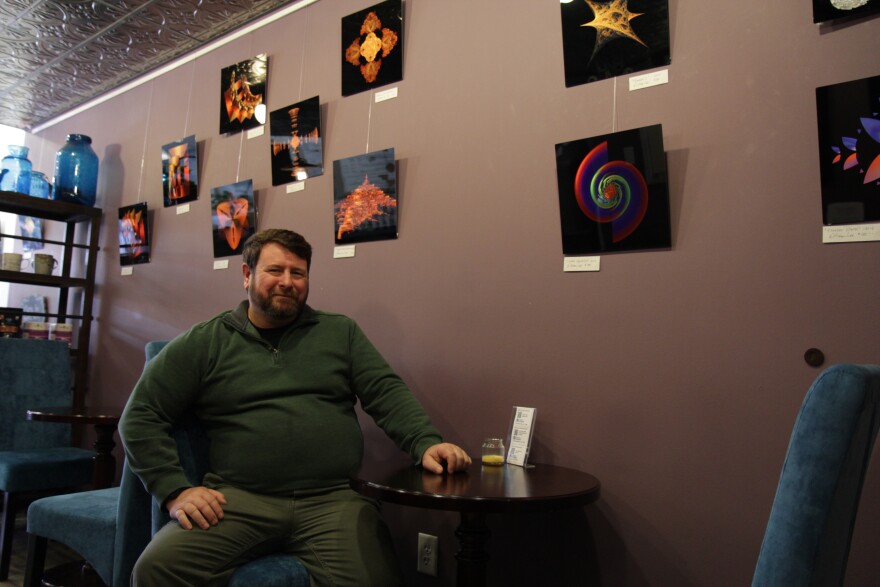 Bill Lee with some of his artwork at Boheme Coffee Lounge in Anchorage. (Photo by Graelyn Brashear, KSKA-Anchorage)