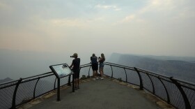 Smoke from the Dragon Bravo Fire moves over the Grand Canyon from the North Rim blocking the view for tourists at the Desert View overlook Monday, July 14, 2025, in Grand Canyon National Park, Ariz. (AP Photo/Ross D. Franklin)