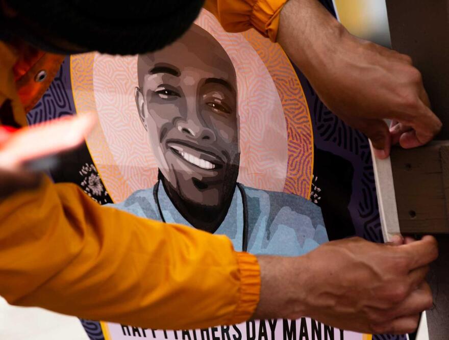 Supporters of Manuel Ellis hang a poster with his photo during a celebration in Tacoma's Hilltop neighborhood.