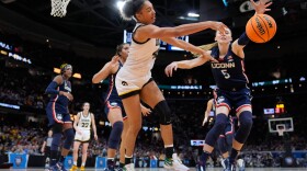Iowa forward Hannah Stuelke passes around UConn guard Paige Bueckers (5) during the second half of a Final Four college basketball game in the women's NCAA Tournament, Friday, April 5, 2024, in Cleveland.