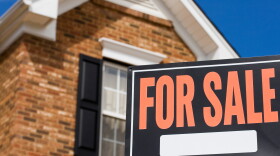 Home for sale - a sign in front of a brick house