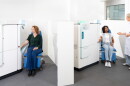  two large machines  in action drawing blood from two patients while one lab worker supervises.   