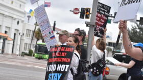 People stand along South Orange Avenue in downtown Orlando on Saturday, holding signs as passing drivers honk in response during the No Kings Day rally.