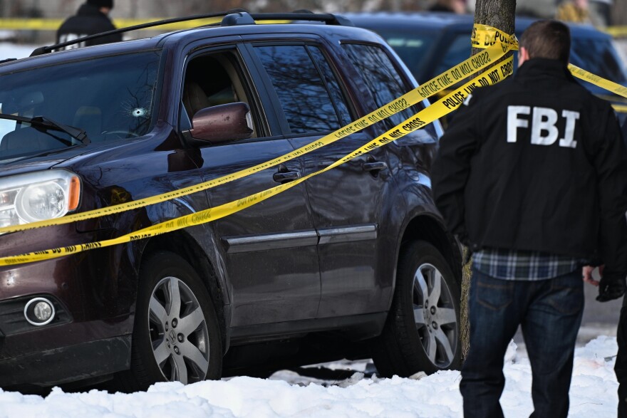 A bullet hole is seen in the windshield as law enforcement officers work the scene of a shooting involving federal law enforcement agents Wednesday, Jan. 7, 2026, in Minneapolis.
