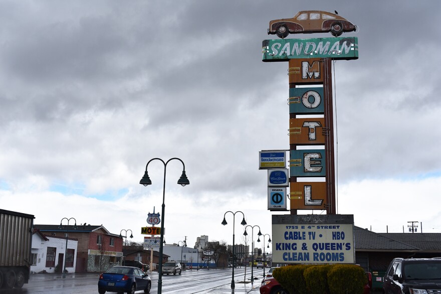 An old, faded sign stands tall with the letters for "motel" stacked high. 