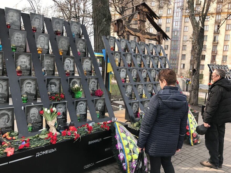 Passersby pay tribute to activists who were killed during 2014 anti-government protests near the Maidan, Kiev's main square.