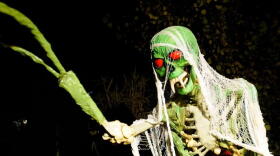 a green skeleton with red eyes serving as a Halloween decoration.