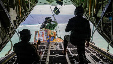 From left, U.S. Air Force Senior Airmen Mark Weinstein and Cody Raymond, 374th Air Expeditionary Wing loadmasters, drop humanitarian bundles during an airdrop as part of Operation Christmas Drop 2025 at the Federated States of Micronesia, Guam, Dec. 10, 2025.