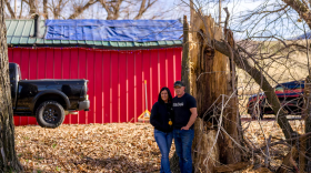 Owners of a Logan coffee shop stand beside the trunk of a massive fallen tree that crushed the roof of their red roastery behind them.