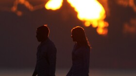 FILE - A couple walks along a jetty as the sun rises over the Atlantic Ocean, Wednesday, June 28, 2023, in Bal Harbour, Fla.