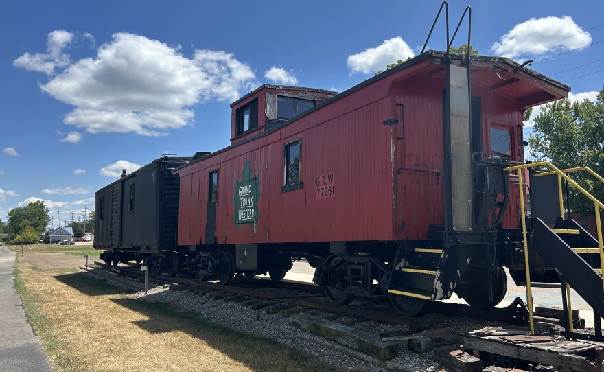 A red and a black railcar sit on a small stretch of railroad