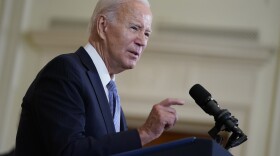 a man in a suit speaks at a podium